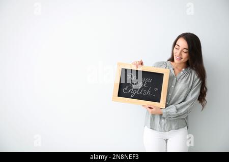 Junge Lehrerin mit Tafel und Wörtern Sprechen sie Englisch? Auf hellem Hintergrund. Platz für Text Stockfoto