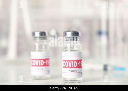 Fläschchen und Spritze mit Coronavirus-Impfstoff auf dem Lichttisch Stockfoto