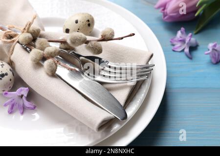 Festlicher Ostertisch mit Eiern und wunderschönen Weidenzweigen auf hellblauem Holzhintergrund, Nahaufnahme Stockfoto