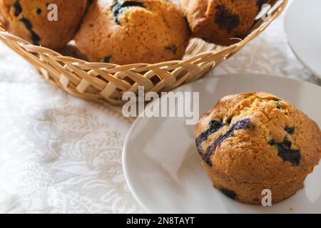 Frisch gebackene Blaubeer-Muffins im Korb und auf dem Teller vorne mit Platz für Text Stockfoto