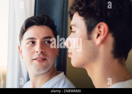 Ein schwules Paar, das einen besonderen Moment am Morgen am Fenster teilt. Homosexuelle romantische Zärtlichkeit. Stockfoto