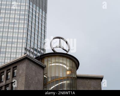 Mercedes-Stern auf dem Dach des berühmten Junior-Hauses in der Innenstadt. Großes Emblem am Kaiserplatz. Ein Wolkenkratzer im Büro Stockfoto
