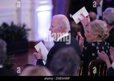 Washington, Vereinigte Staaten. 11. Februar 2023. US-Präsident Joe Biden und First Lady Dr. Jill Biden applaudieren als Sänger und Songwriter Brad Paisley auf einer After-Dinner-Party für Gouverneure und ihre Ehepartner im Weißen Haus während der Wintersitzung der National Governors Association in Washington, DC am 11. Februar 2023. Anmerkung: Das Zimmer war mit magentafarbenem Licht beleuchtet. Kredit: Chris Kleponis/Pool über CNP/dpa/Alamy Live News Stockfoto