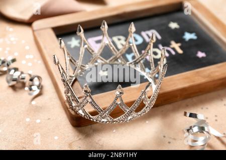 Tafel mit Text FÜR ABSCHLUSSBALL UND Diadem auf beigefarbenem Hintergrund, Nahaufnahme Stockfoto