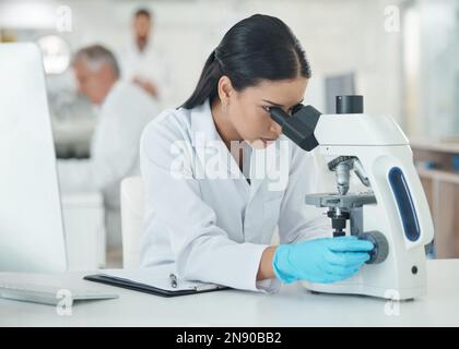 Mit verfeinerten wissenschaftlichen Methoden in ihrer Analyse. Ein junger Wissenschaftler, der ein Mikroskop in einem Labor benutzt. Stockfoto