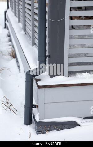 Regenwassersystem für hölzerne Veranda des Cottage, gefroren und mit Schnee bedeckt Stockfoto