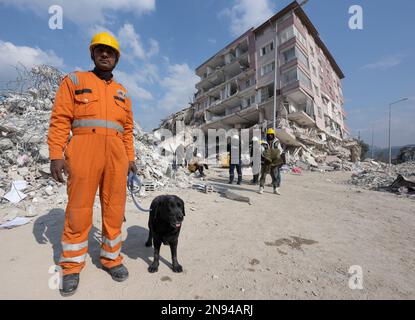 Antakya, Türkei. 11. Februar 2023. Hundeführer Pawan Kumar aus Indien wartet mit seinem Suchhund Roxy auf seine nächste Mission. Tausende von Opfern werden immer noch unter den Trümmern verdächtigt. Teams von Helfern aus der ganzen Welt arbeiten im Katastrophengebiet. (Zu dpa 'Waiting for Death' aus 12.02.2023) Kredit: Boris Roessler/dpa/Alamy Live News Stockfoto