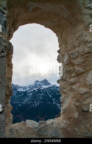 Füssen, Deutschland - Januar 14. 2023 - Blick durch ein Fenster der Ruine Falkenstein in Richtung Alpen Stockfoto