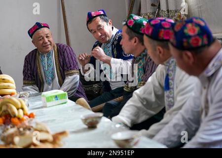 (230212) -- URUMQI, 12. Februar 2023 (Xinhua) -- Sulayman Abdu (1. l), ein Muqam-Künstler, unterhält sich mit anderen Volkskünstlern in seiner Residenz in Muqam Village, Lukqun Town, Shanshan County, Nordwestchina's Autonomer Region Xinjiang Uygur, 11. Januar 2023. Der Muqam ist die traditionelle Kunst der uigurischen Volksgruppe in Xinjiang. (Xinhua/Zhao Ge) Stockfoto