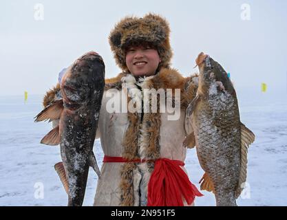 (230212) -- URUMQI, 12. Februar 2023 (Xinhua) -- Ein junger Mann zeigt Fisch während eines Fischereitourismusfestivals im Winter im Fuhai County, Nordwesten Chinas Autonome Region Xinjiang Uygur, 7. Januar 2023. Xinjiang, das über günstige natürliche Bedingungen und mehrere erstklassige Skigebiete verfügt, hat die Hauptrolle in der boomenden Industrie übernommen und ist eines der beliebtesten Wintertouristenziele des Landes. (Xinhua/Li Xiang) Stockfoto