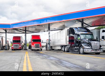 Große Industriestandards Sattelzugwagen mit Sattelanhängern stehen auf dem Parkplatz der Tankstelle und füllen die Sattelzugwagen mit Dieselkraftstoff bis Stockfoto