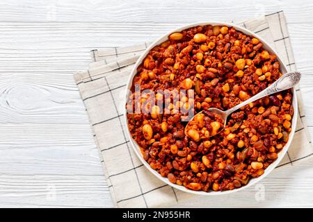 Bohnen und Würstchen mit Kidney Beans, großen Nordbohnen, Schwarzäugigen Erbsen, Pinto Beans, Kichererbsen, Fleisch- und Tomatensoße in Backform auf weißem w Stockfoto