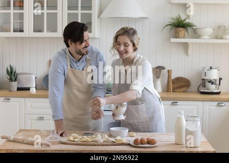 Ein glückliches, positives, junges Paar, das sich liebt und Schürzen trägt Stockfoto