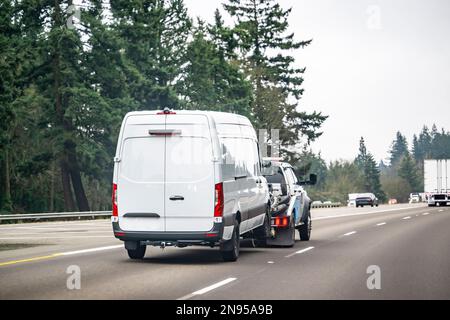 Industriegüter leistungsstarker Abschleppwagen, der gebrochene Fracht in einem Minivan schleppt und zur Autobahnreparatur fährt, um Motorwartungen und -Inspektionen durchzuführen Stockfoto