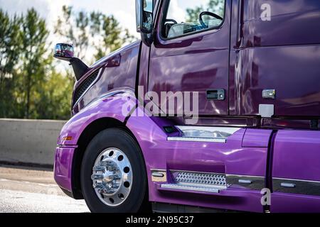 Großer industrieller Langtransporter, glänzender, lilafarbener Sattelzugmaschine mit erweiterter Kabine für Lkw-Fahrer, der Fracht im Auflieger transportiert, der auf t fährt Stockfoto