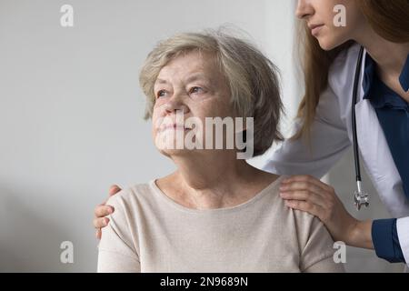 Rücksichtsvolle, traurige, ältere Patientin, die neben einem Arzt sitzt Stockfoto