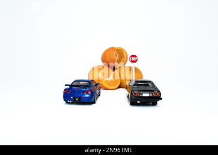 Ein Foto nach einigen Änderungen versuchen 2 Spielzeugautos der Skyline von nissan, Orangen zu erreichen. Das Konzept, nicht zu viel zu essen, auch wenn es heilend ist. Stockfoto