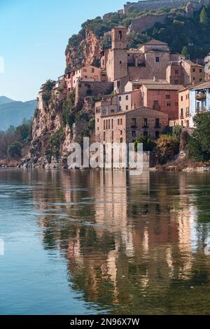 Altstadt von miravet mit der templerburg auf dem Gipfel und dem fluss ebro, der an einem sonnigen Tag leise fließt. Stockfoto