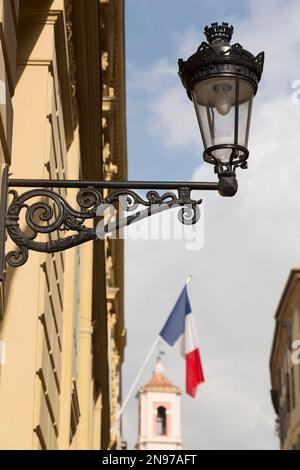 Frankreich, Nizza, kunstvoll verzierte Lampe, französische Flagge und Uhrturm auf dem Place du Palais de Justice, Vieille Ville (Altstadt). Stockfoto