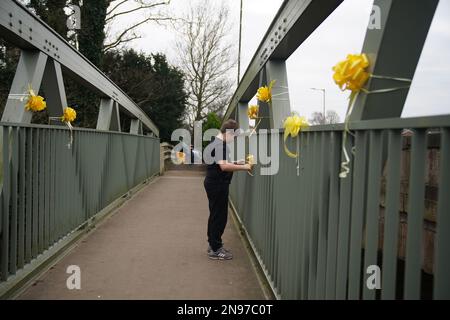 HINWEIS FÜR REDAKTEURE: DIE ERLAUBNIS EINES ERZIEHUNGSBERECHTIGTEN, DIE Einem Jungen ERTEILT WURDE, bindet ein gelbes Band mit einer Botschaft der Hoffnung an eine Brücke über den Fluss Wyre in St. Michael's auf Wyre, Lancashire, während die Polizei ihre Suche nach der vermissten Frau fortsetzt, Nicola Bulley, 45, Die zuletzt am Morgen des 27. Januar gesehen wurde, als sie ihren Hund auf einem Fußweg am nahe gelegenen Fluss Wyre spazieren ging. Foto: Sonntag, 12. Februar 2023. Stockfoto