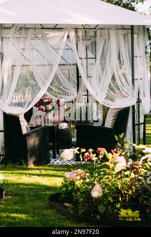 Gartenlaube im Hinterhof, überdachter Zelt, Lounge, Entspannungsbereich im august, schwedischer Garten Stockfoto