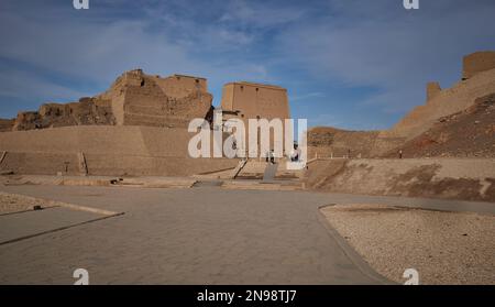 Der Tempel von Edfu in Edfu, ägyptischer Blick bei Tageslicht, der den Haupteingang mit Besuchern und Wolken am Himmel im Hintergrund zeigt Stockfoto