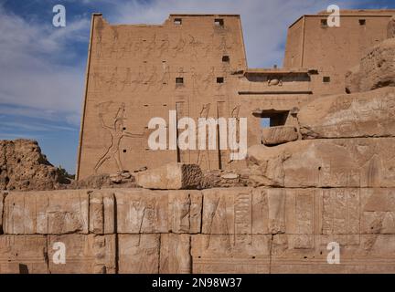 Der Tempel von Edfu in Edfu, ägyptischer Blick bei Tageslicht, der den Haupteingang mit Besuchern und Wolken am Himmel im Hintergrund zeigt Stockfoto