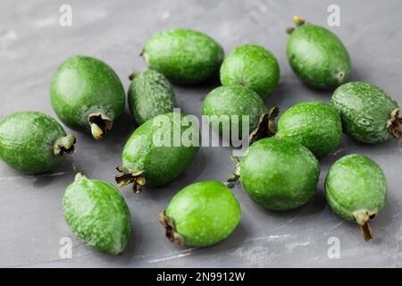 Grüne Feijoa-Früchte auf grauem Betonhintergrund. Tropische Fruchtfeijoa. Ein Set reifer Feijoa-Früchte. Speicherplatz kopieren Stockfoto