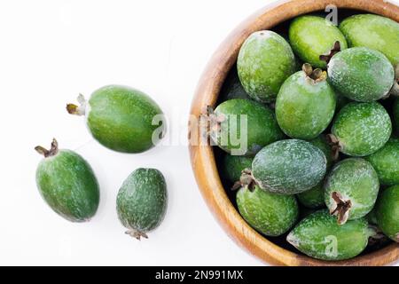 Grüne Feijoa-Früchte auf einer Holzplatte auf weißem Hintergrund. Tropische Fruchtfeijoa. Ein Set reifer Feijoa-Früchte. Speicherplatz kopieren Stockfoto