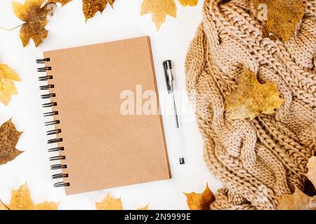 Strickpullover, Notizbuch, Ahornblätter im Herbst auf weißem Hintergrund. Herbstzusammensetzung. Thanksgiving-Tageskonzept. Flach liegend, Draufsicht, Kopierbereich. Komm Schon Stockfoto