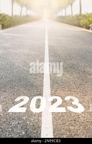 Frohes neues Jahr 2023. 2023 auf Asphaltstraße geschrieben. Beginnen Sie das neue Jahr bei Sonnenaufgang. Herausforderung, Planung und Opportunity-Konzept. Vertikales Foto Stockfoto