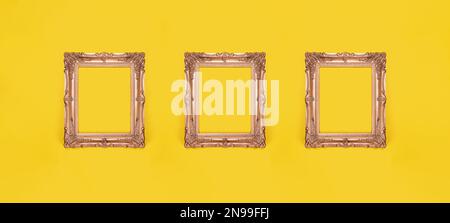 Drei leere, reich verzierte goldene Bilderrahmen auf gelbem Wandhintergrund in der Ausstellungsgalerie Stockfoto