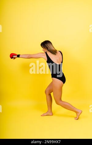 Frau macht High-Kick, Tae-bo. Sportliche Passform für Damen mit perfektem Körperkick und Schlägen mit den Beinen Stockfoto