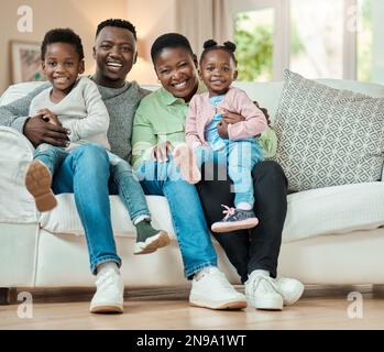 Eine perfekte Familie. Aufnahme einer liebevollen, jungen vierköpfigen Familie, die auf ihrem Sofa zu Hause im Wohnzimmer sitzt. Stockfoto