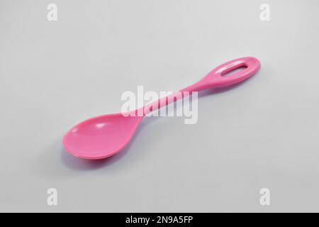 Kleiner rosafarbener Kunststofflöffel isoliert auf weißem Hintergrund. Stockfoto