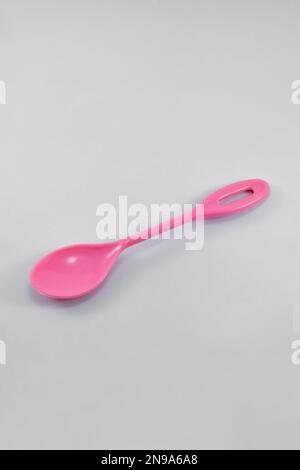 Kleiner rosafarbener Kunststofflöffel isoliert auf weißem Hintergrund. Stockfoto
