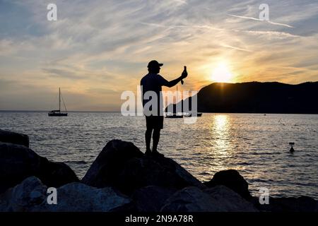 Mann macht Fotos, blaue Stunde mit Handy im Hafen von Vernazza, Cinque Terre, Provinz La Spezia, Ligurien, Italien Stockfoto