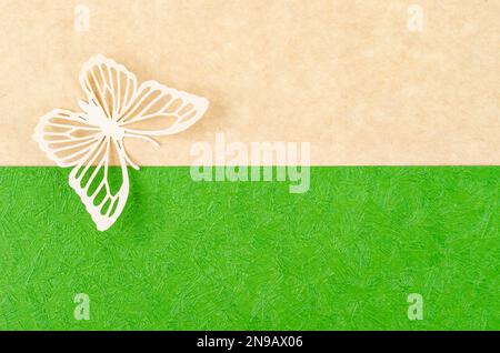 Schmetterling aus geschnitztem Papier oder Schnitt auf grünem und gelbem Hintergrund mit leerem Platz für Ihren Text oder Ihre Nachricht. Stockfoto