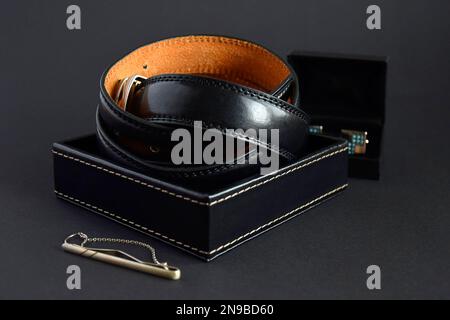 Verdrehter Männer Ledergürtel in schwarz in Box auf dunklem Hintergrund, elegante Accessoires, Nahaufnahme. Stockfoto