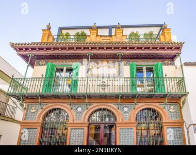 Wunderschönes altes Gebäude mit Keramikfliesen an der Fassade und schmiedeeisernen Balkonen im Zentrum der Altstadt von Triana, Sevilla, in A Stockfoto