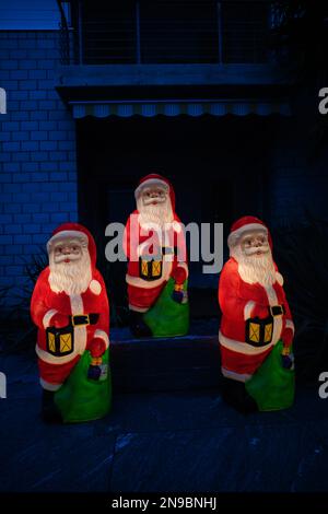 Figuren von drei Weihnachtsmännern bei Nacht mit Lampen im Hof des Hauses Stockfoto