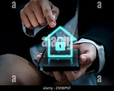 Smart-Home-Technologie-Konzept. Leuchtendes digitales Sicherheits-Schloss-Symbol Hologramm erscheint auf dem Smartphone in den Händen von Geschäftsleuten. SmartHome Sicherheit Stockfoto