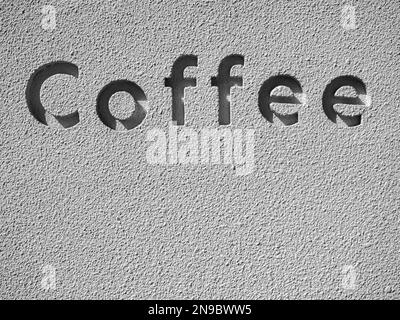 Das Wort „Kaffee“, die Buchstaben, die in die Wörter auf der Grunge-Betonwand eingeprägt sind, mit Platz für Kopien, vertikal. Licht und Schatten in der Schrift auf der Th Stockfoto