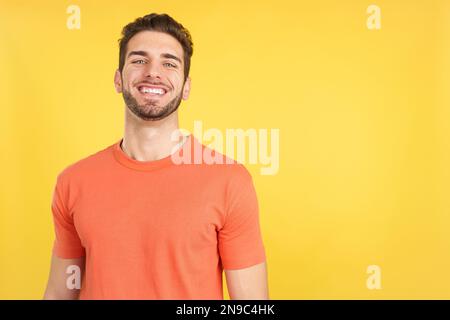 Ein gutaussehender Mann, der mit gekreuzten Armen vor der Kamera lacht Stockfoto