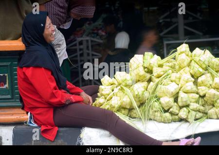 Ehrliches Porträt einer Indonesierin, die Ketupat verkauft, während sie lacht. Stockfoto