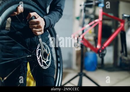 Mechaniker, der in der Werkstatt ein Spezialfahrrad für die Montage des Radschlüssels für die Scheibenbremse zusammenstellt Stockfoto