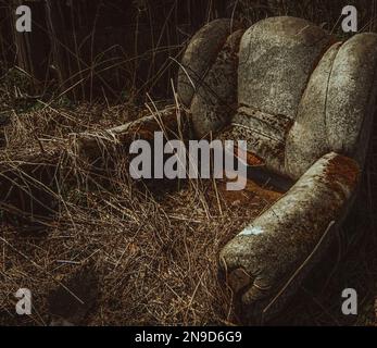 Eine Nahaufnahme eines alten und dreckigen Sofas und trockener Äste darauf in einem dunklen Raum Stockfoto