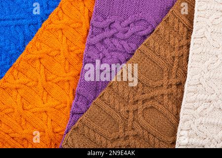 Gestrickter Hintergrund: Blau, lila, braun, orange und beige. Großer Strickstoff mit Muster. Nahaufnahme einer Strickdecke. Stockfoto