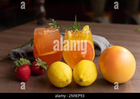 Fruchtgetränk, hausgemachte Limonade oder Sangria mit Zitrusfrüchten und Beeren auf Holzhintergrund, erfrischender Cocktail für heiße Sommertage Stockfoto
