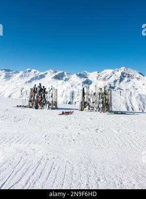 Skier und Snowboards auf Regalen vor dem Skirestaurant mit schneebedeckten Bergen dahinter, Hochgurgl, Tirol, Österreich Stockfoto
